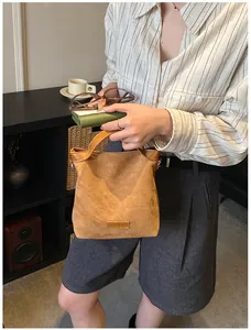 Détail d'un mini sac à main vintage en daim marron avec anses en cuir et étiquette logo