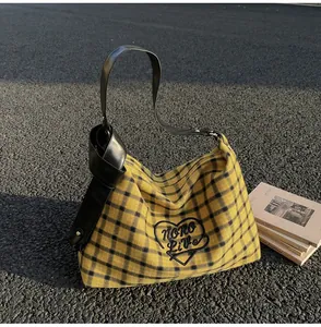 Detail of yellow and black checkered hobo bag with heart embroidery on asphalt
