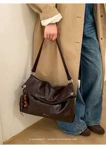 Detail of vintage dark brown leather tote bag with wooden bead charm and metal rings