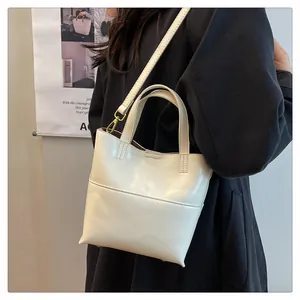 Detail of a creamy white vintage leather bucket bag worn as a crossbody for daily style