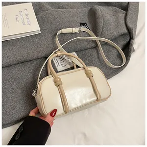 Détail du sac Boston avec bandoulière réglable et doubles poignées en cuir crème