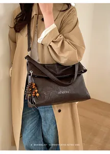 Detail of dark brown leather tote bag featuring wooden bead tassel and retro design