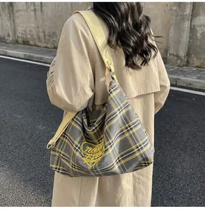 Detail of grid patterned tote bag with yellow heart embroidery on beige trench coat