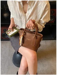 Detailansicht der braunen Ledertasche mit goldener Hardware und Holzperlenanhänger