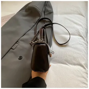 Detail of a glossy dark brown leather handbag featuring a sleek metallic clasp lock