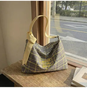 Detailed shot of plaid wool tote bag with heart embroidery and yellow leather strap