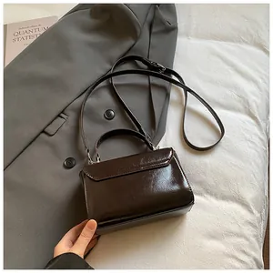 Detail of vintage oil wax leather handbag featuring adjustable long strap and top handle