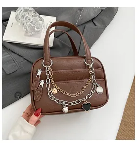 Detailed view of brown lychee leather handbag featuring triple metallic decorative chains