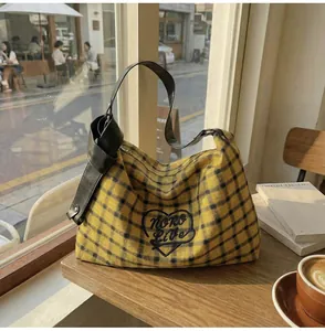 Close-up of yellow checkered hobo bag with heart embroidery on a cafe table
