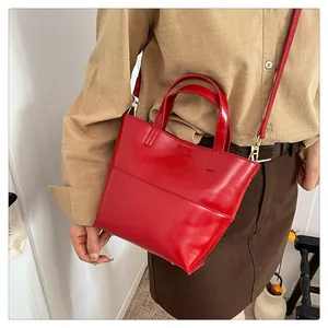 Detail of red glossy leather handbag with gold hardware and removable shoulder strap