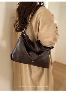 Close-up of deep brown tote bag with glossy wrinkled texture on model shoulder
