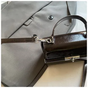 Detail of dark brown structured handbag with silver hardware and vintage leather texture