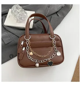 Detail of dark brown lychee leather bag with layered metal chains and heart charms