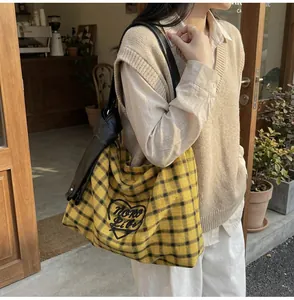 Detail of yellow plaid canvas tote with wide black shoulder strap and heart embroidery