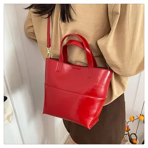 Polished red bucket bag with gold hardware worn by a model in a minimalist setting