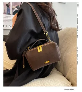 Close-up of a vintage dark brown suede Boston bag with gold zippers and metal tag details