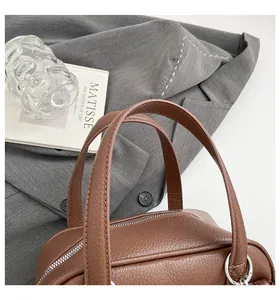Close-up of the textured brown lychee leather and silver zipper on the briefcase