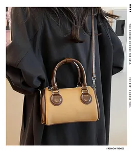 Detalle de un bolso cilíndrico vintage bicolor en lona caqui y cuero marrón con bandolera