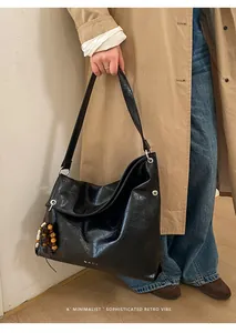 Detail of black faux leather hobo bag with vintage beads and glossy pleated texture