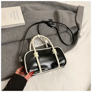 Détail d'un sac Boston chic noir et blanc porté par un mannequin dans un cadre urbain