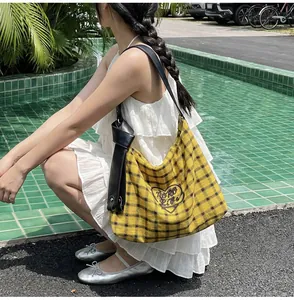Close-up of yellow checkered tote bag with heart embroidery and knotted leather strap