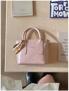 Detail der rosa Kunstledertasche mit böhmischem Holzperlenanhänger auf einem Holztisch