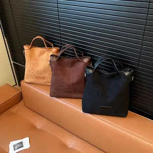 Sacs à main en daim vintage pour femmes en marron et noir sur un canapé en cuir
