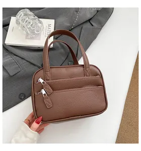 Detailed view of a brown pebbled leather briefcase featuring dual front zipper pockets