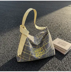 Close-up of yellow check tote bag with NORO LOVE embroidery on asphalt background