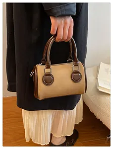 Detalle del bolso Boston de sarga beige con ribetes de cuero marrón y herrajes plateados
