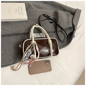 Détail sac Boston marron foncé avec téléphone pour échelle et breloque chien