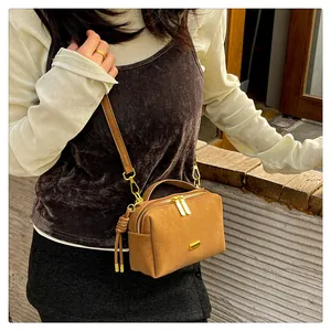 Retro brown suede Boston bag styled on a shoulder with minimalist gold hardware and strap