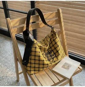 Detail of checkered tote bag with heart embroidery and knotted leather strap on chair