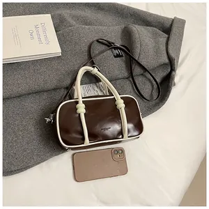 Détail du sac Boston rétro avec poignées contrastées et lettrage doré de marque