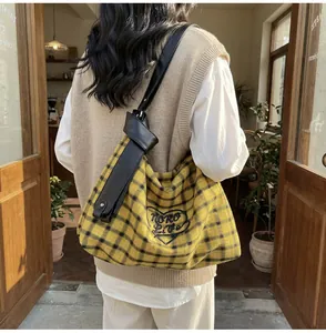 Close-up of checkered tote bag featuring a heart embroidery and knotted leather strap