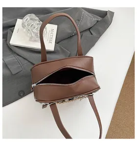Close-up of brown litchi grain leather briefcase with silver zipper and metal chain detail