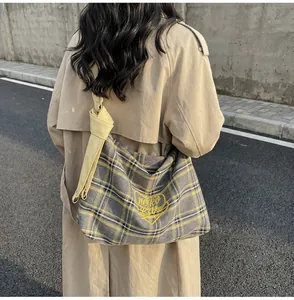 Detail of grey plaid tote bag featuring yellow heart embroidery and knotted wide strap