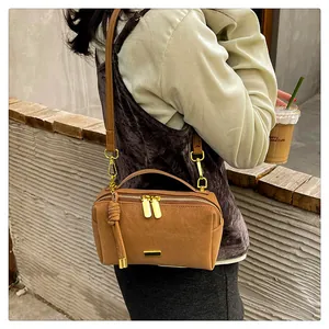 Detail showing the brown faux leather Boston bag with gold zippers and slim shoulder strap