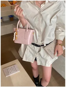 Detailansicht der rosa Ledertasche mit Perlenanhänger und Fashion & Bags Aufdruck