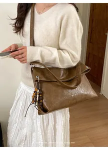 Close-up of vintage brown tote bag with lucky letter print and beaded tassel charm