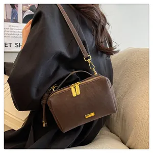 Detailed close-up of brown suede Boston bag with golden zipper and metal hardware