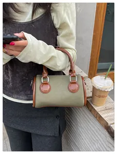 Detalle del bolso cilíndrico de lona verde militar con asas de cuero y herrajes de plata