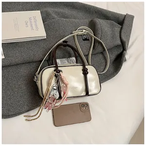 Gros plan détaillé du sac Boston crème avec breloque peluche sur manteau en laine