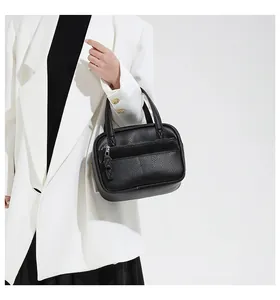Side view of a black pebble leather briefcase held by a model in a white blazer