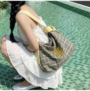 Detail of yellow plaid tote bag featuring heart embroidery and woven shoulder strap