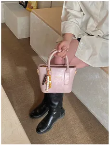 Rosa Eimertasche aus PU-Leder mit Perlenanhänger und goldenem Logo im Lifestyle-Szenario