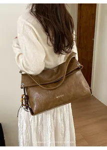 Detail of dark brown faux leather tote with vintage texture and wooden bead charm