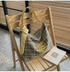 Detail of checkered shoulder bag with heart embroidery and stylish yellow knotted strap