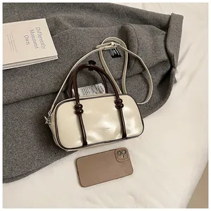 Vue détaillée du sac Boston crème avec poignées nouées et lettrage de marque raffiné