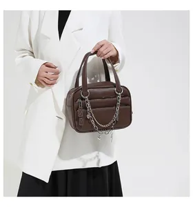 Detail of dark brown lychee textured handbag with mixed-metal chain and heart charm